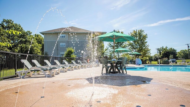 Ein Poolbereich mit Liegestühlen, einer Wasserspielen und Sonnenschirmen.