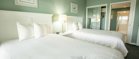Een hotelkamer met twee bedden, een nachtkastje met een lamp en een spiegel.