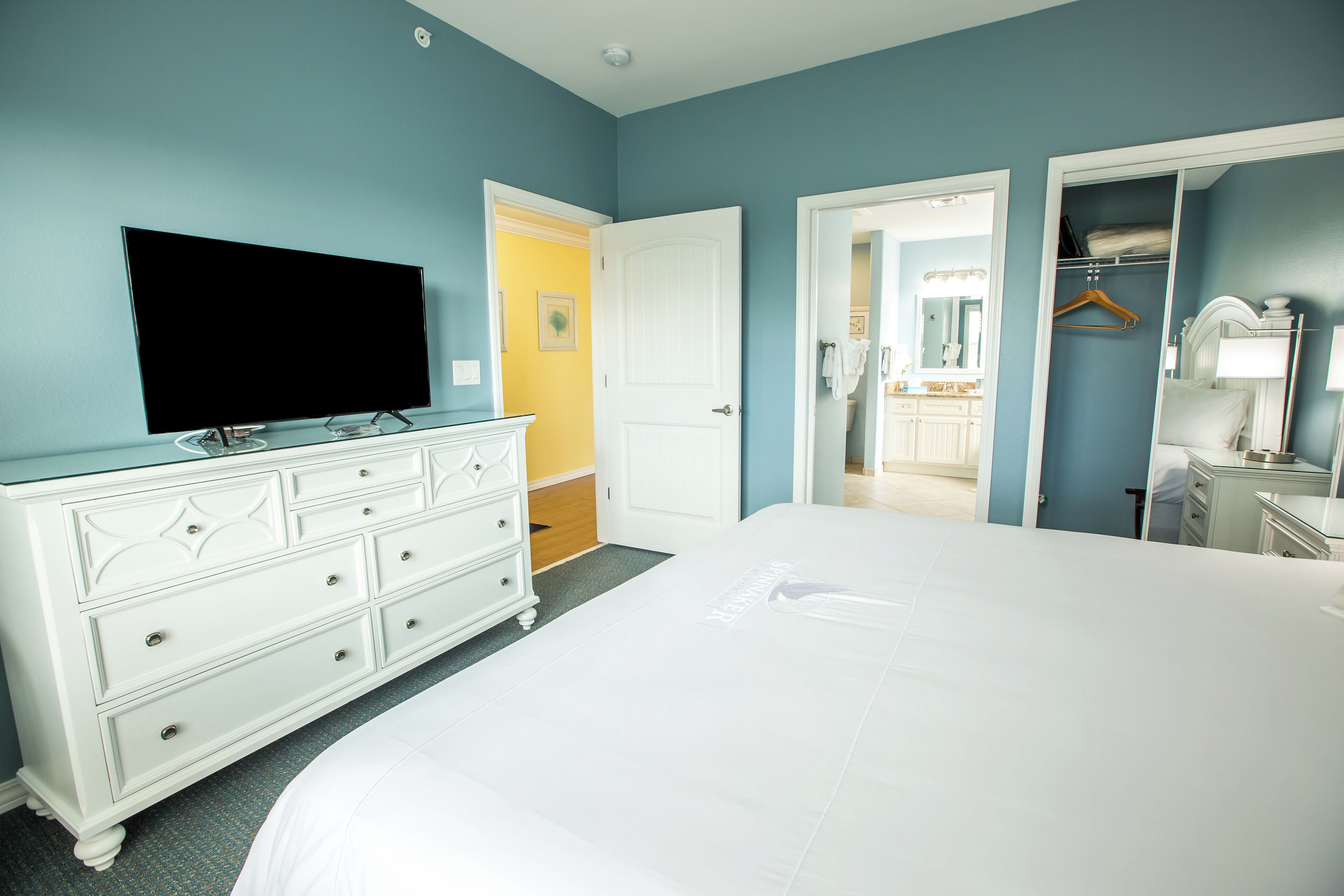 Un dormitorio con una cama grande, un aparador, un televisor y un vestidor.
