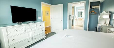 Un dormitorio con una cama grande, un aparador, un televisor y un vestidor.
