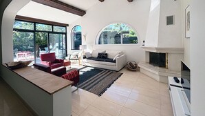 Uma sala de estar moderna com lareira, janelas amplas e um sofá vermelho.