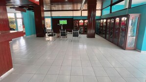 Un hall d’entrée spacieux, doté d’un sol carrelé, d’un téléviseur fixé au mur et d’une série d’armoires à vitrines le long d’un des murs.