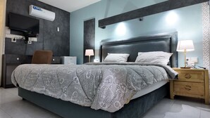 Une chambre moderne avec un grand lit, des lampes de chevet, une télévision et une armoire.