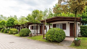 A row of small, single-story cabins with a covered porch, surrounded by well-maintained lawns and trees.