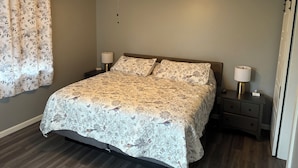 Ein Schlafzimmer mit einem Bett, zwei Nachttischen, einem Deckenventilator und einem Fenster mit Vorhängen.