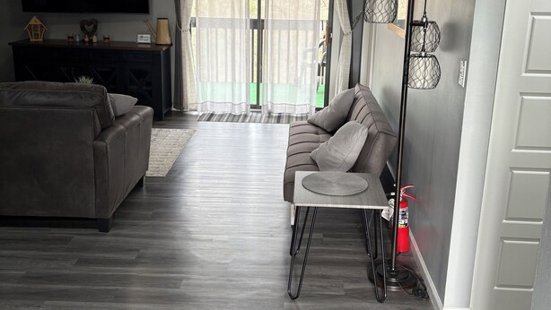 Ein modernes Wohnzimmer mit einem grauen Sofa, einem kleinen Tisch und einem Fernseher.