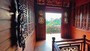 A wooden corridor with intricate carvings, a wooden door leading to a balcony, and a railing. - Mai Viên Homestay & Restaurant (Hue)