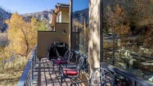 A balcony with outdoor seating, a barbecue grill, and a view of autumn trees and mountains. - Warm Springs 4-bedroom, 4 bath. Gourmet kitchen, fitness room, pool, and hot tub (Ketchum)