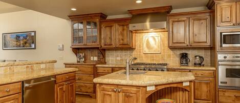 A kitchen with wooden cabinets, granite countertops, a stainless steel dishwasher, a gas stove, and an oven.