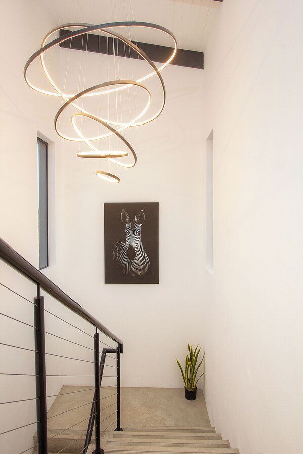 A staircase with a modern light fixture and a zebra artwork on the wall.