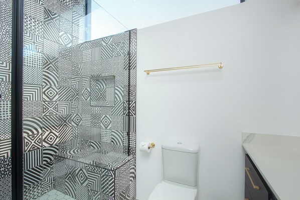 A bathroom with patterned tiles, a toilet, and a towel rack.