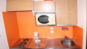Eine kleine Küche mit Mikrowelle, Kaffeemaschine und kleinem Kühlschrank.