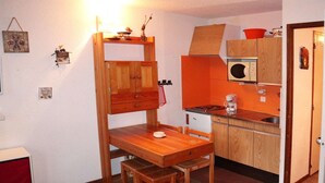 Eine kleine Küche mit Holzausstattung, einem Esstisch und einer Mikrowelle.