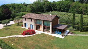 A two-story house with a patio area, a small garden, and a view of the surrounding forest. - Villa Montello Pool Jacuzzi Ac Wifi  (Volpago del Montello)