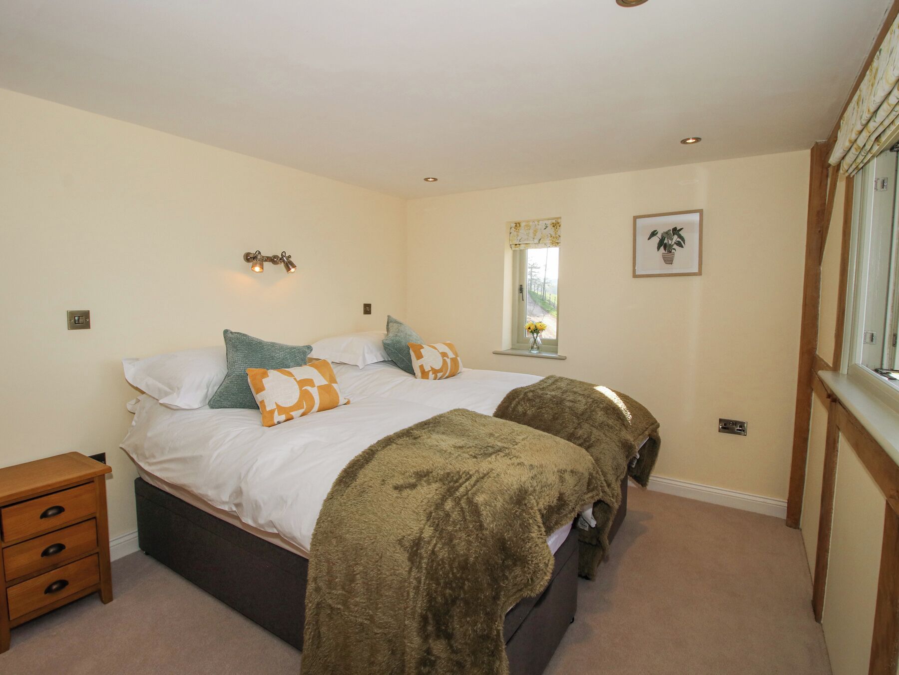 A bedroom with a bed, bedside tables, a window with a view, and a framed picture on the wall.