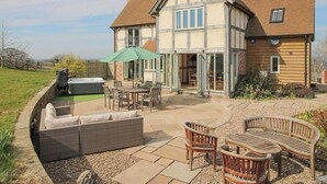A two-story house with a patio area featuring outdoor furniture and a hot tub. - Cuckoo Pen Cottage (Tenbury Wells)