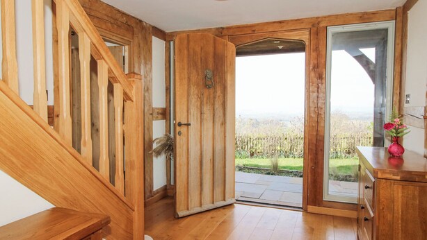 A wooden staircase leading to a door with a view of a garden. - Cuckoo Pen Cottage (Tenbury Wells)