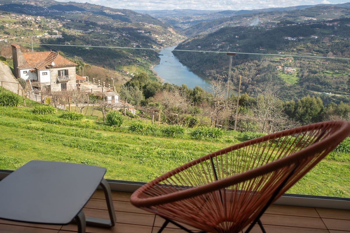 Eine Terrasse mit Blick auf einen Fluss, ein Sessel und ein Tisch.