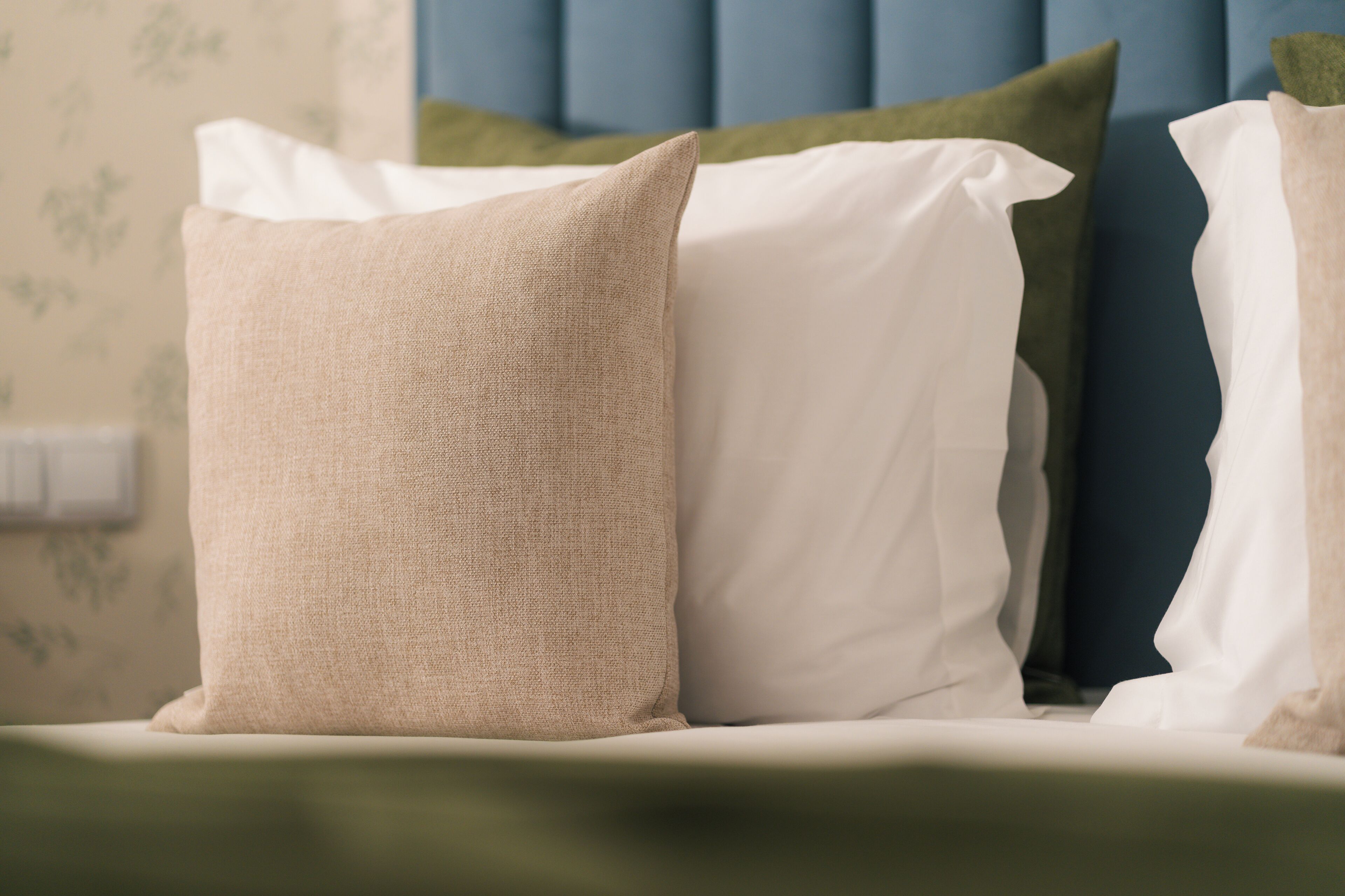 A bed with three pillows in different colors.