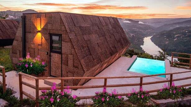 A stone building with a pool, surrounded by a wooden fence and pink flowers. - Quinta Casal da Silva 1951 (Marco de Canaveses)