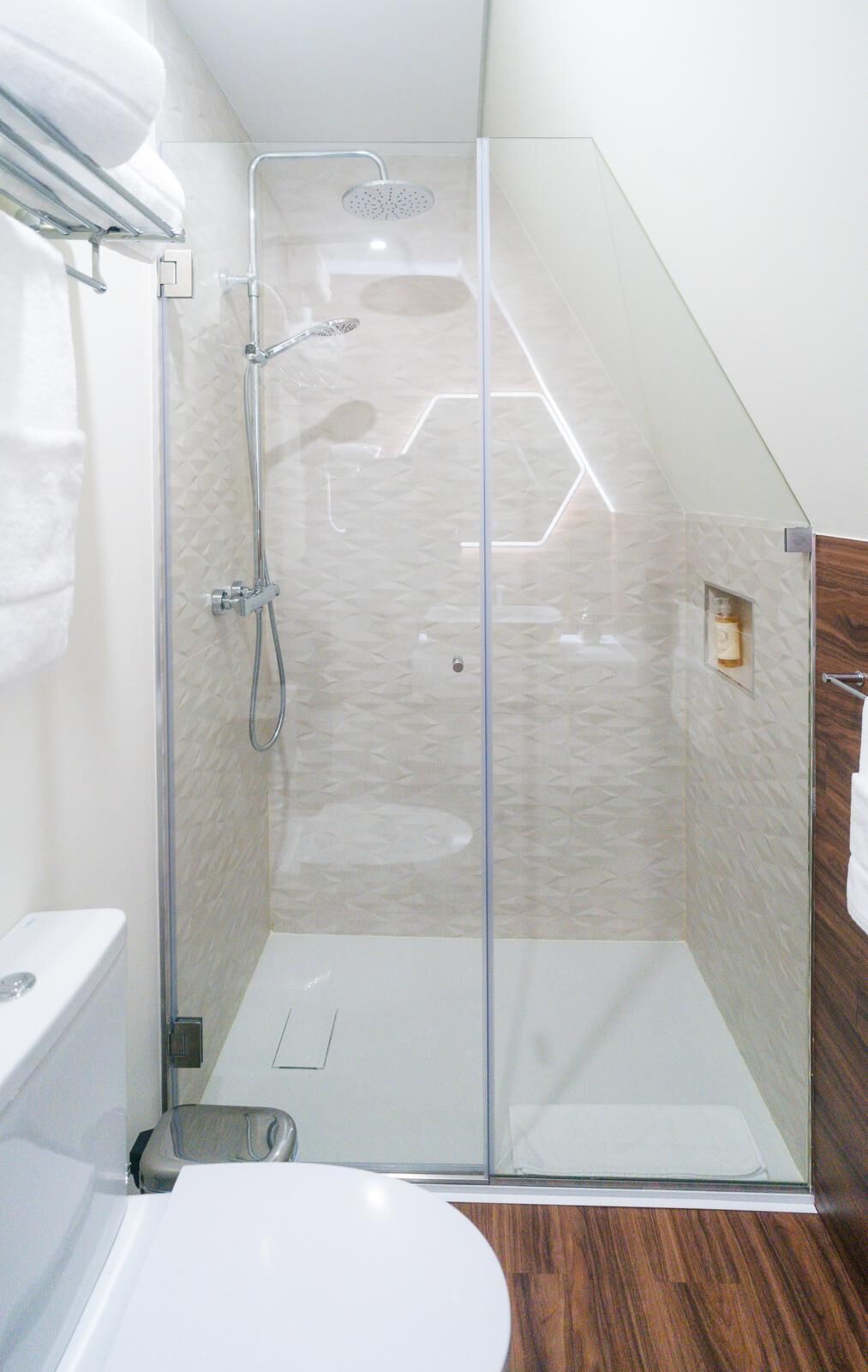 A glass-enclosed shower stall with a handheld showerhead and a wall-mounted faucet.