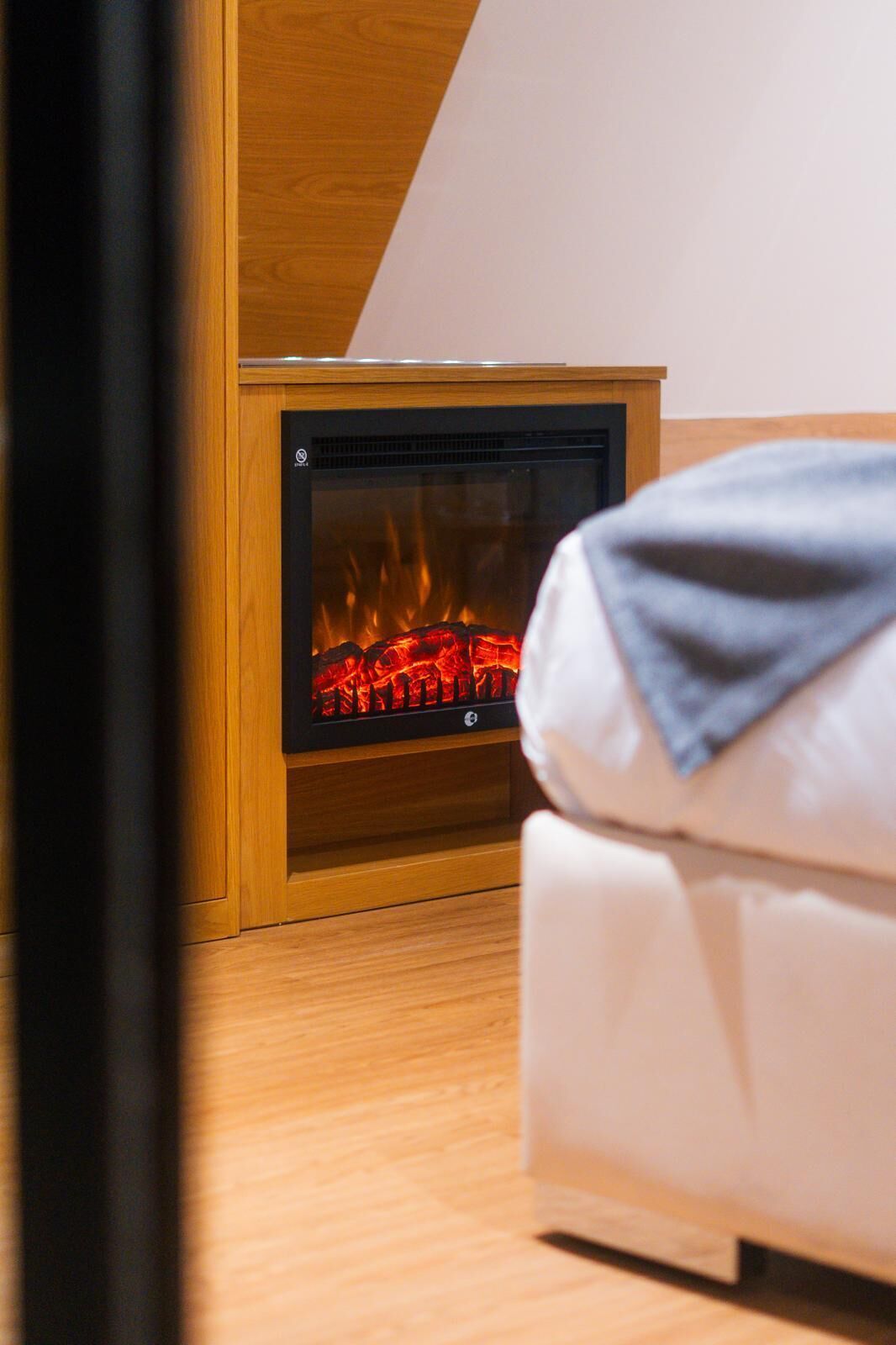 A room with a wood-burning stove, a white sofa, and wooden flooring.