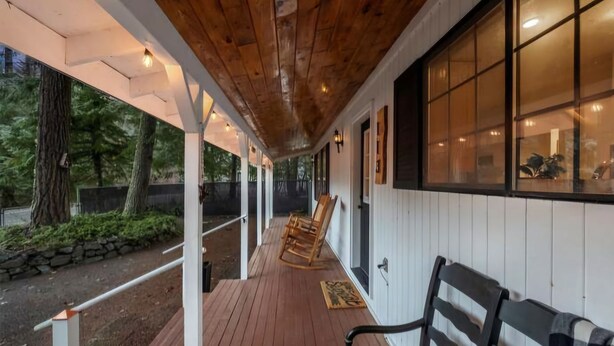 A covered porch with wooden flooring, a rocking chair, and a bench.