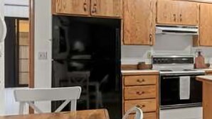 A kitchen with wooden cabinets, a stove, and a dining table with chairs.