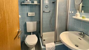 A bathroom with a toilet, a shower enclosure, a sink, and a mirror.