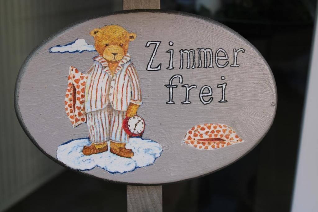 A wooden sign with a teddy bear illustration and the text "Zimmer frei" (room available).