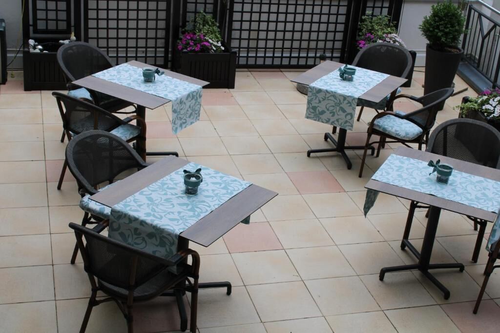 Un patio con cuatro mesas y sillas, cada una con mantel y un pequeño adorno.