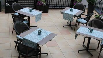 Un patio con cuatro mesas y sillas, cada una con mantel y un pequeño adorno.