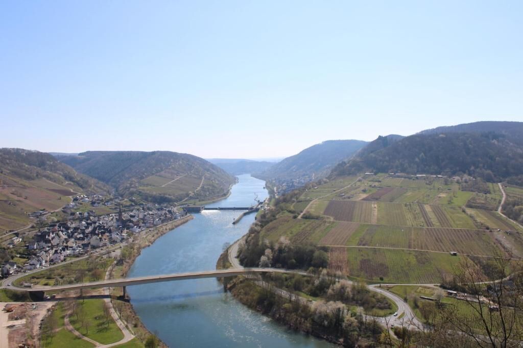Une rivière traverse une vallée, et un pont ainsi qu’une petite ville se trouvent sur une de ses rives.