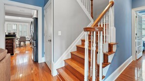 A spacious kitchen with wooden flooring, a dining area, and a staircase with white railings. - Combined 2 homes-9BR/8 BTH, 25 beds Best Location. Perfect for Large Groups (Columbus)