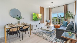 Un salon moderne comprenant un coin repas, un canapé, un téléviseur et un balcon avec vue.