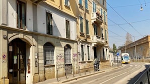 A street with a tram, buildings with balconies, and a clear sky. - Colorful studio- Bramante 41 (Milan)