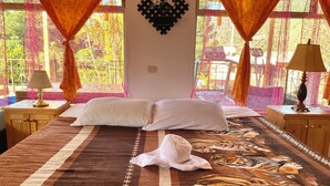 A bedroom with a bed, two bedside tables, a lamp on each table, and a window with curtains. - Hotel Minnesota (San Lucas Tolimán)