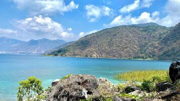 Un paisaje costero con agua azul cristalina, terreno rocoso y abundante vegetación.