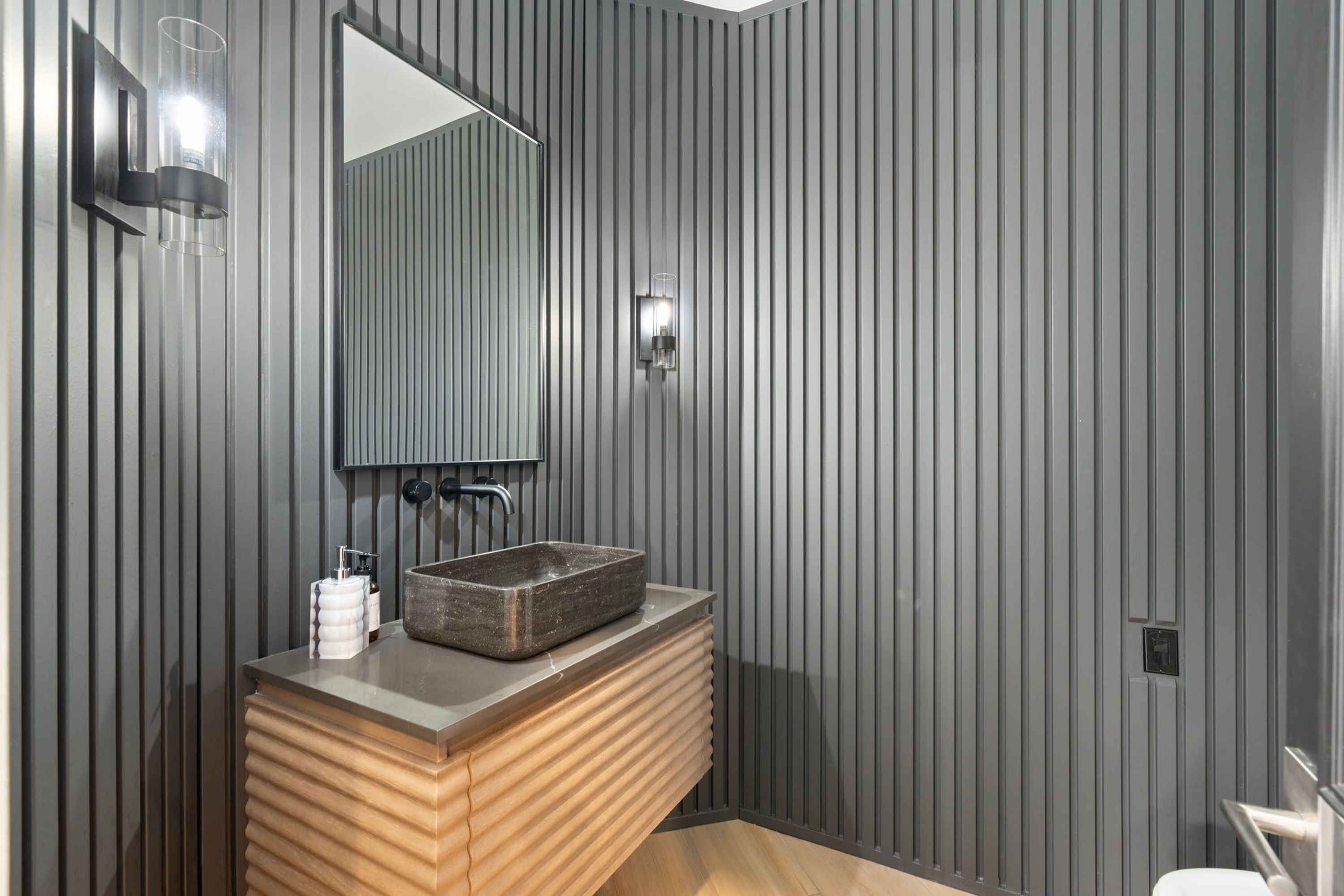 A modern bathroom with a wooden vanity, a vessel sink, and a large mirror.