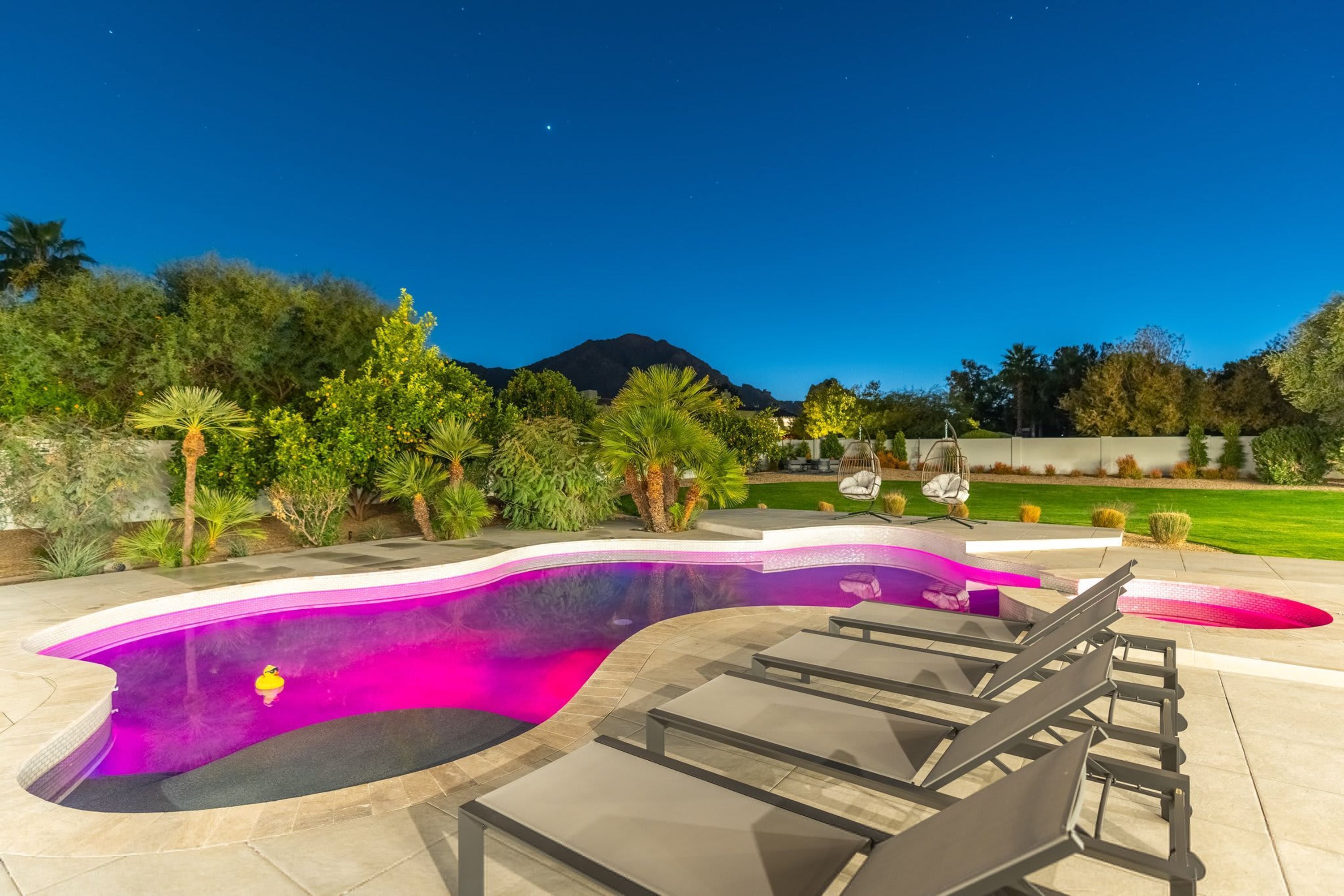 A swimming pool with a curved design, surrounded by lounge chairs and a landscaped garden.