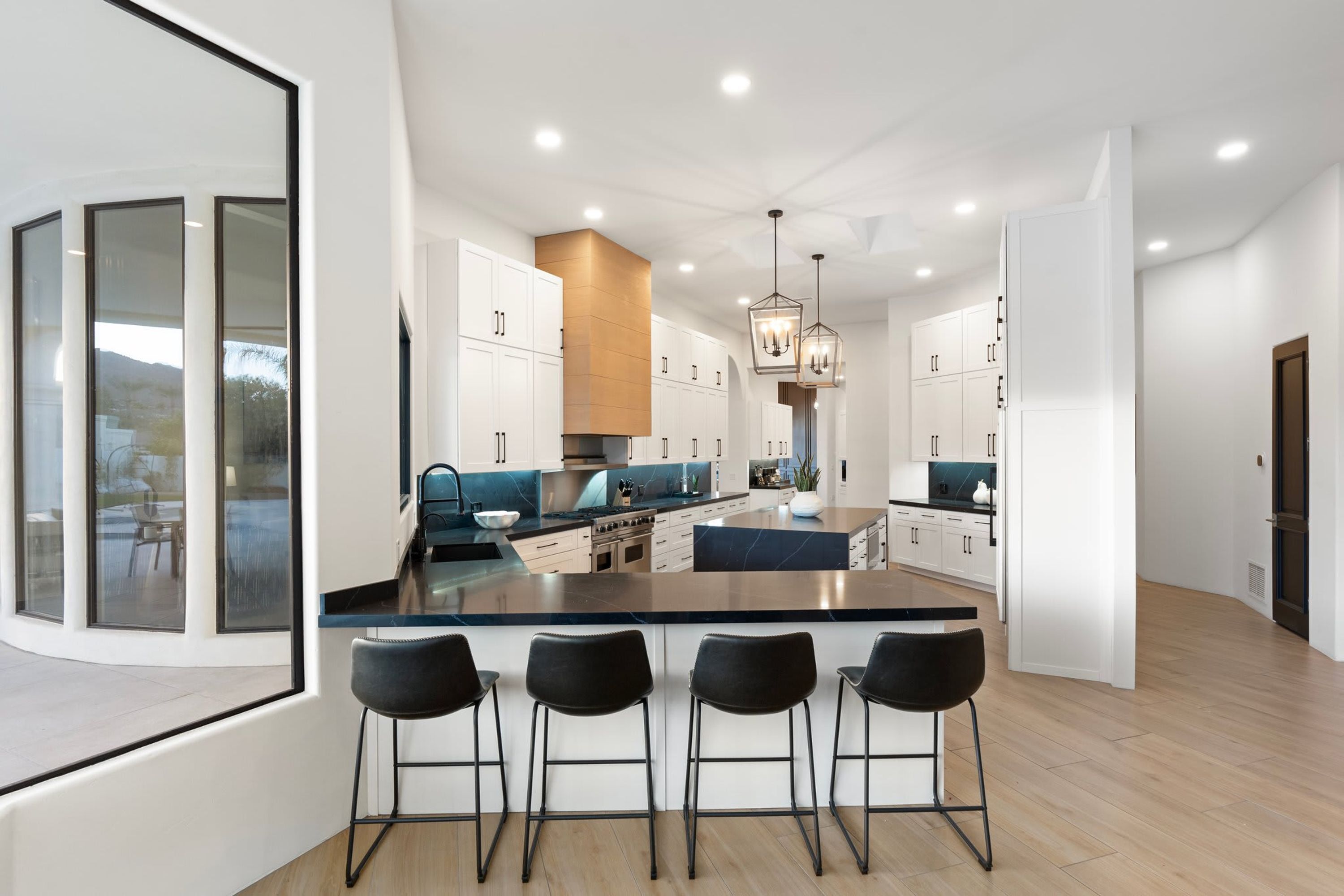 A modern kitchen with a central island, bar stools, and pendant lighting.
