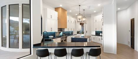 A modern kitchen with a central island, bar stools, and pendant lighting.