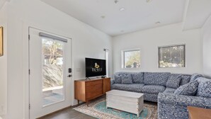 A modern living room with a sofa, a coffee table, a TV, and a wooden cabinet. - Historic Garfield Industrial 1 BR Minutes to DT PHX (Phoenix)