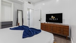 A modern hotel room with a large bed, a wooden dresser, a flat-screen TV, and a wardrobe. - Historic Garfield Industrial 1 BR Minutes to DT PHX (Phoenix)