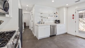 A modern kitchen with white cabinetry, a stainless steel dishwasher, and a built-in oven. - Historic Garfield Industrial 1 BR Minutes to DT PHX (Phoenix)