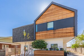 A modern two-story house with a sloped roof, a large window on the upper floor, and a small balcony. - Historic Garfield Industrial 1 BR Minutes to DT PHX (Phoenix)