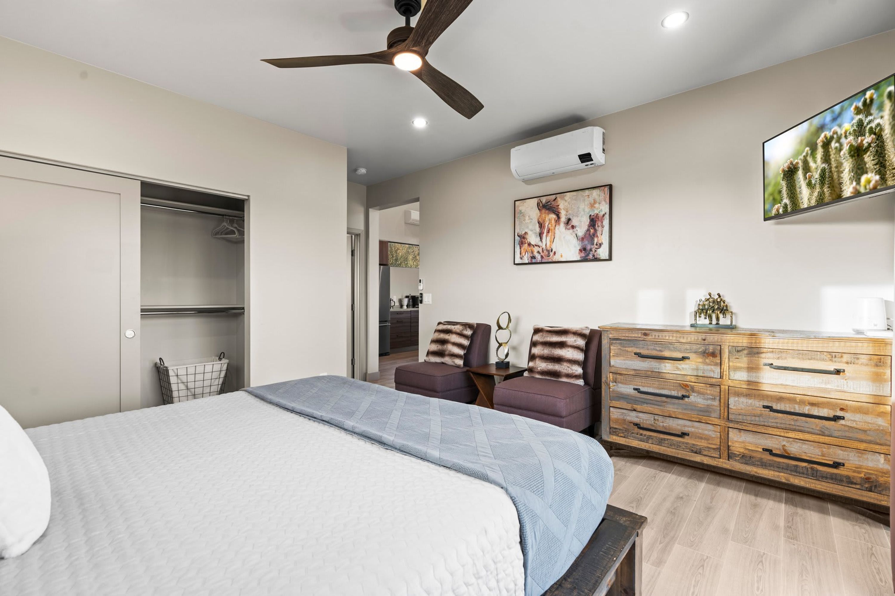 A bedroom with a bed, a wardrobe, a ceiling fan, a dresser, and a TV.