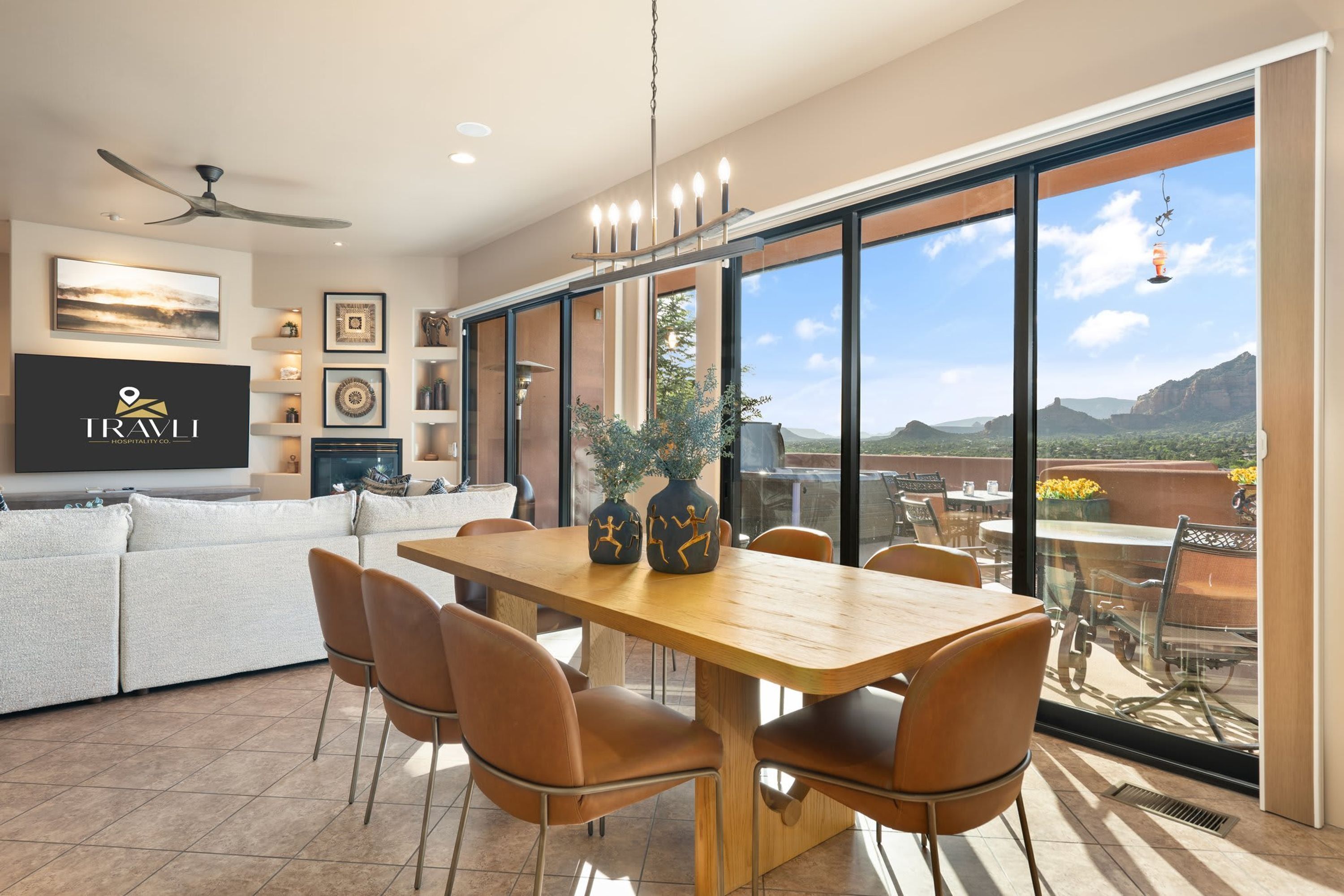 A spacious living area with a wooden dining table, comfortable seating, a large TV, and a view of the outdoors.