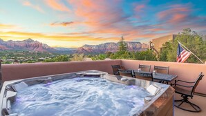 A hot tub with a view of mountains and a sunset.