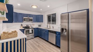 A modern kitchen with blue cabinets, stainless steel appliances, and a built-in dishwasher. - NEW The Mesquite Retreat on Oak Entertainers Oasis (Scottsdale)